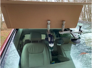 A cardboard box is sitting on top of a car windshield.