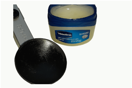 A jar of vaseline next to a measuring spoon.