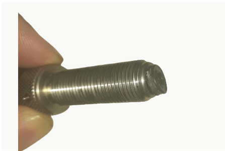 A person is holding a metal bolt in their hand.