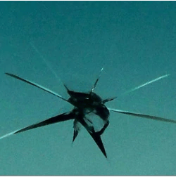 A close up of a cracked windshield with a blue sky in the background