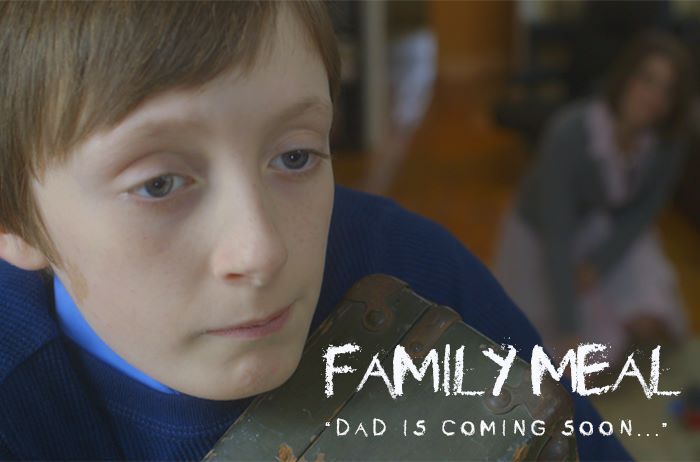 Boy holding chest, looking sad; family in background; text: