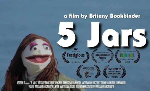 A puppet with pink lipstick and long hair next to 