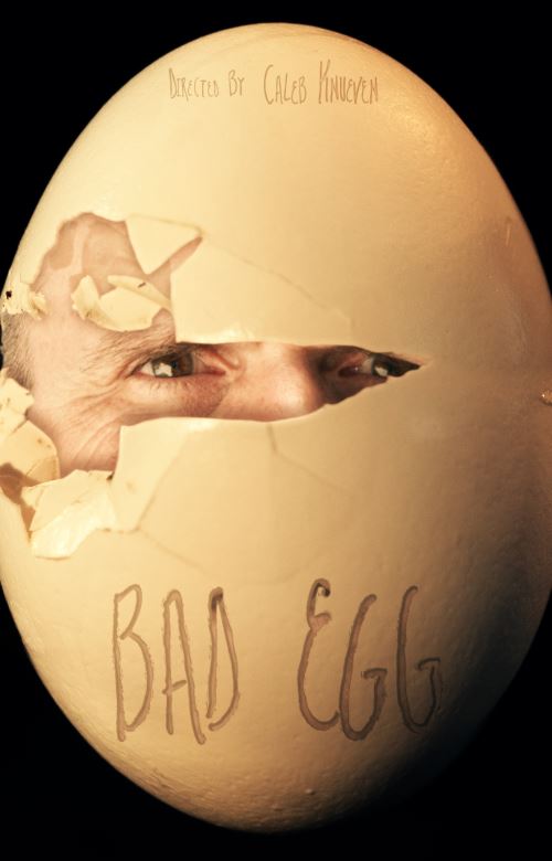 A man's face peers from a cracked egg, title