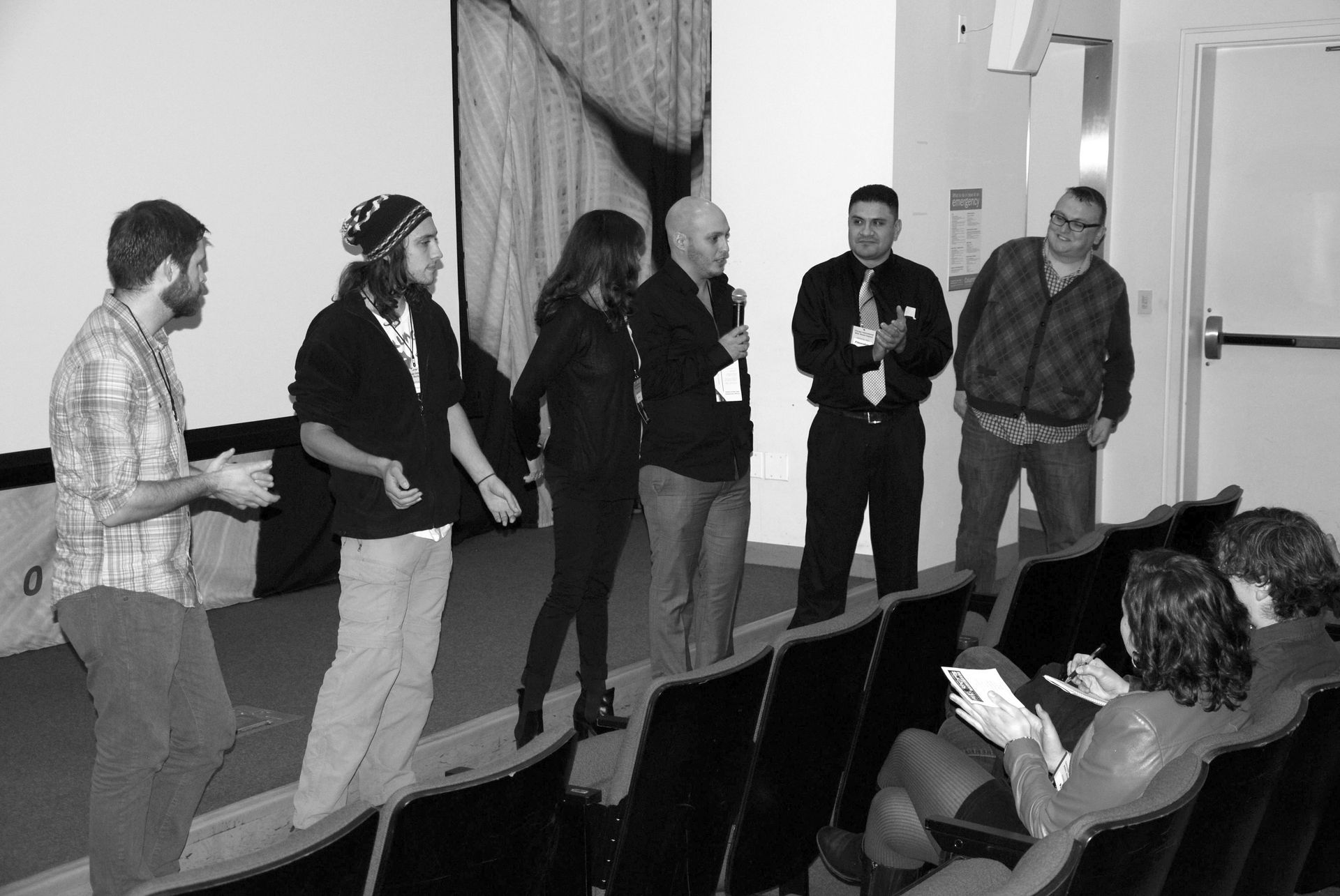 A group of people on a stage; some standing, some in the audience; a presentation.