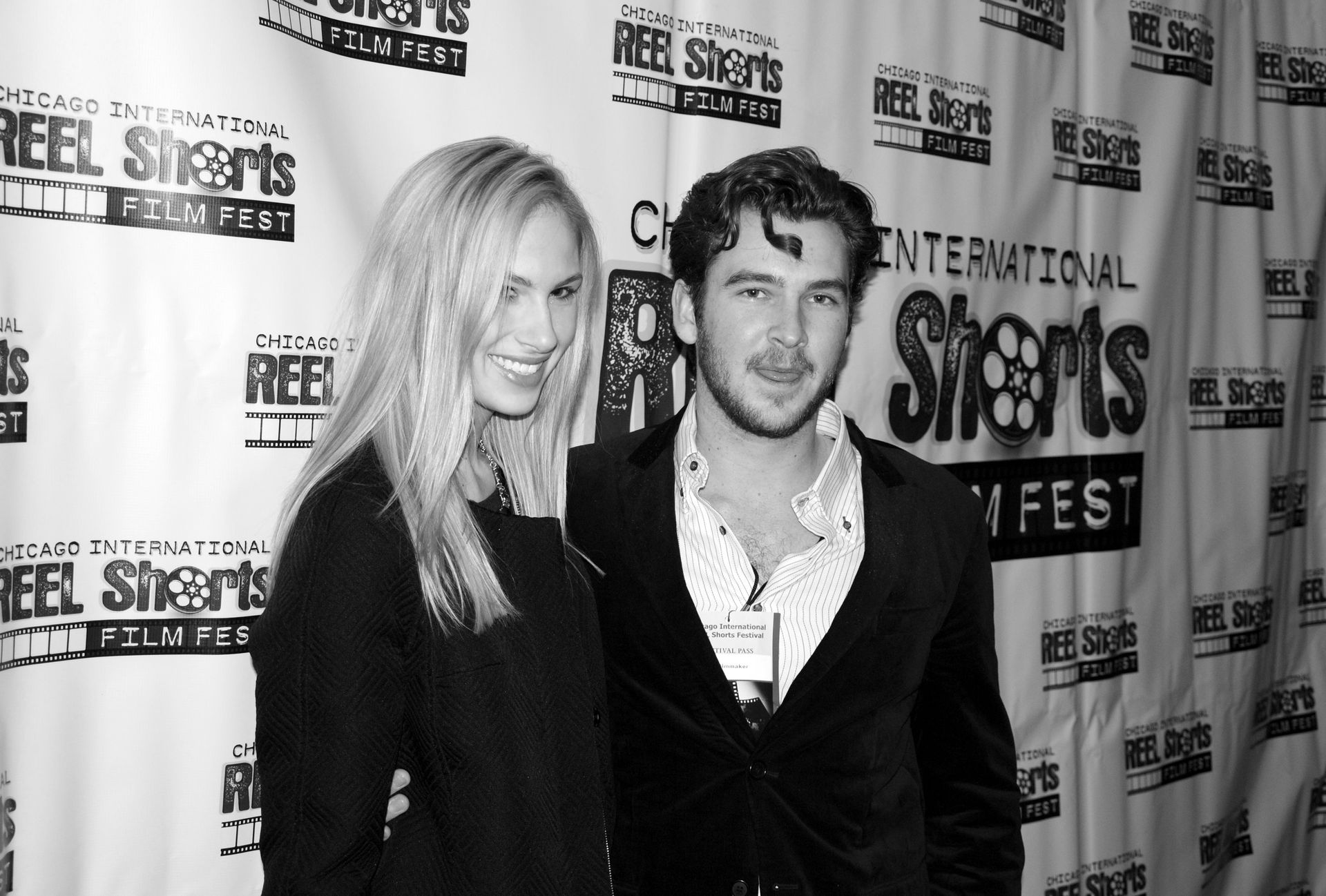 A man and woman pose at a film festival, smiling at the camera. Black and white.