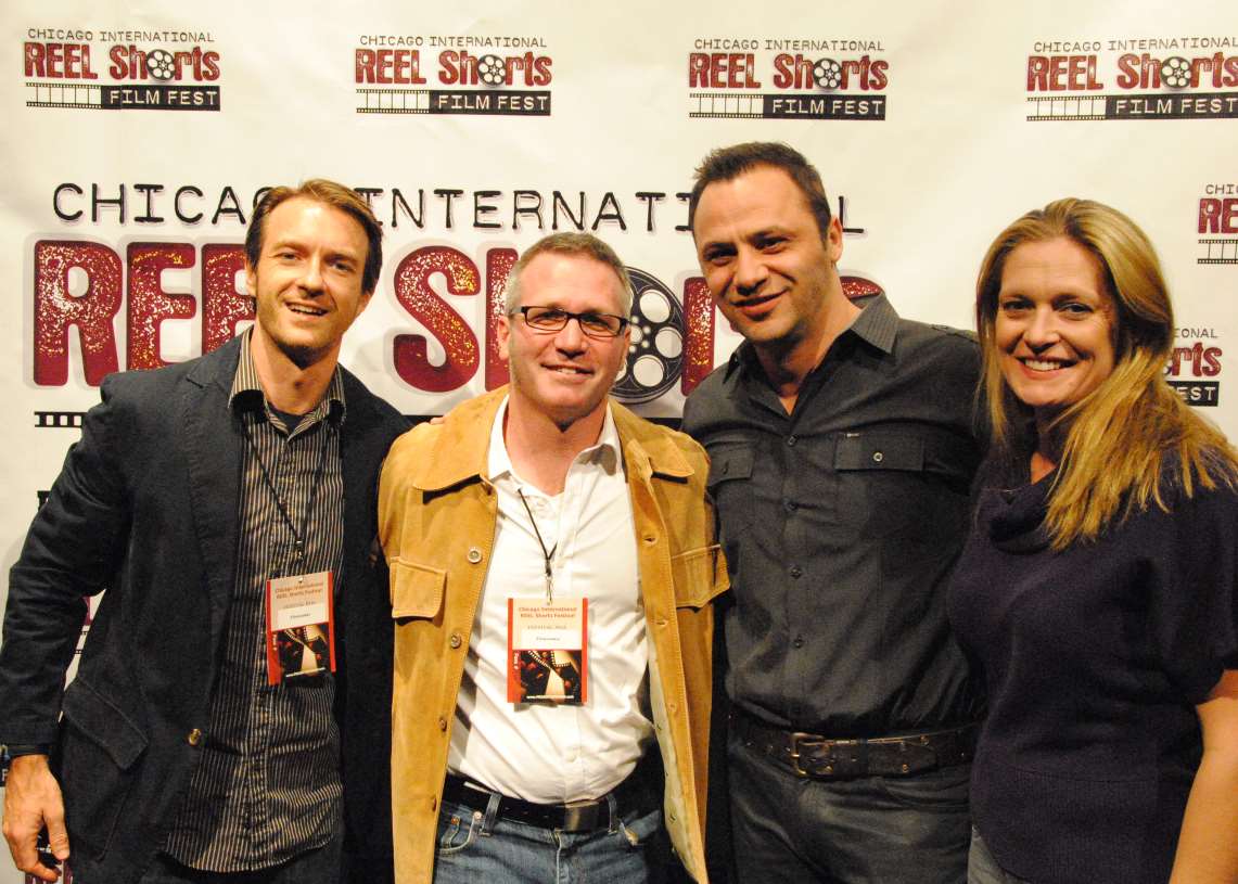 Four people smiling at a film festival. Two men and two women stand in front of a backdrop.