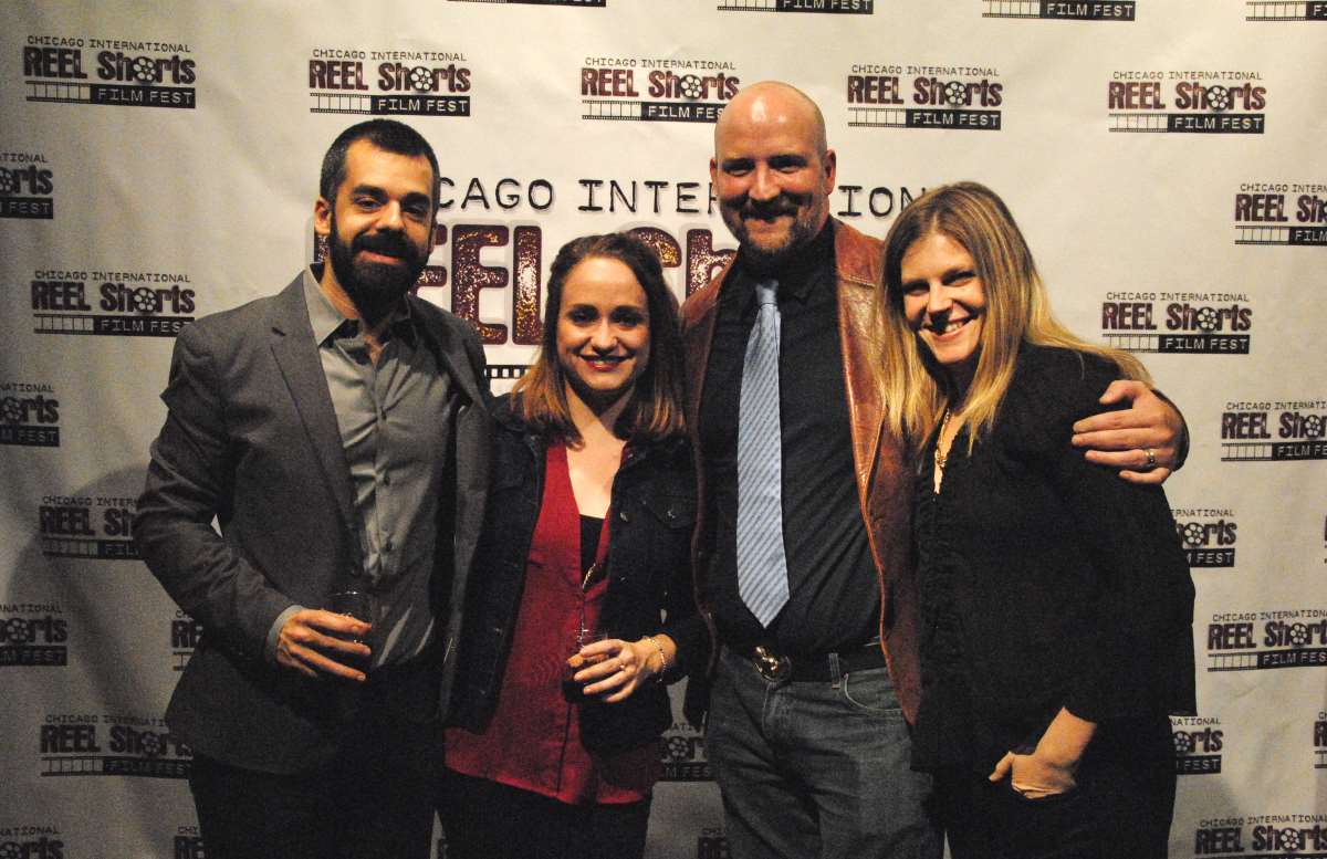 Four people pose at Chicago International Reel Shorts event. Two men, two women, smiling against a banner.