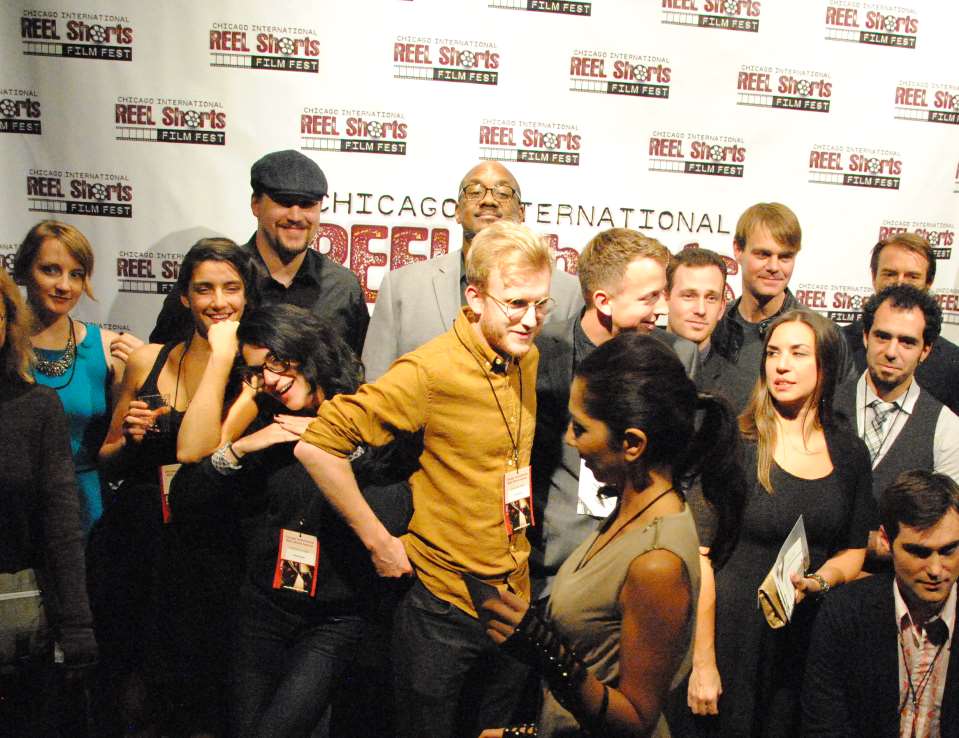 Group of people at a film festival posing on a red carpet, smiling for a photo.