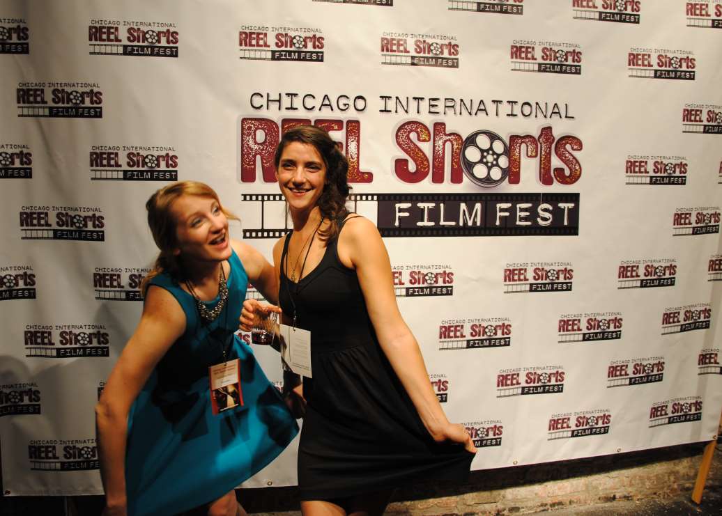Two women smile, posing in front of the 