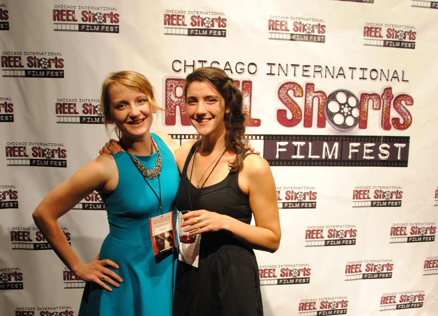 Two women smiling at a Chicago film festival. One wears blue, the other black. Red carpet backdrop.
