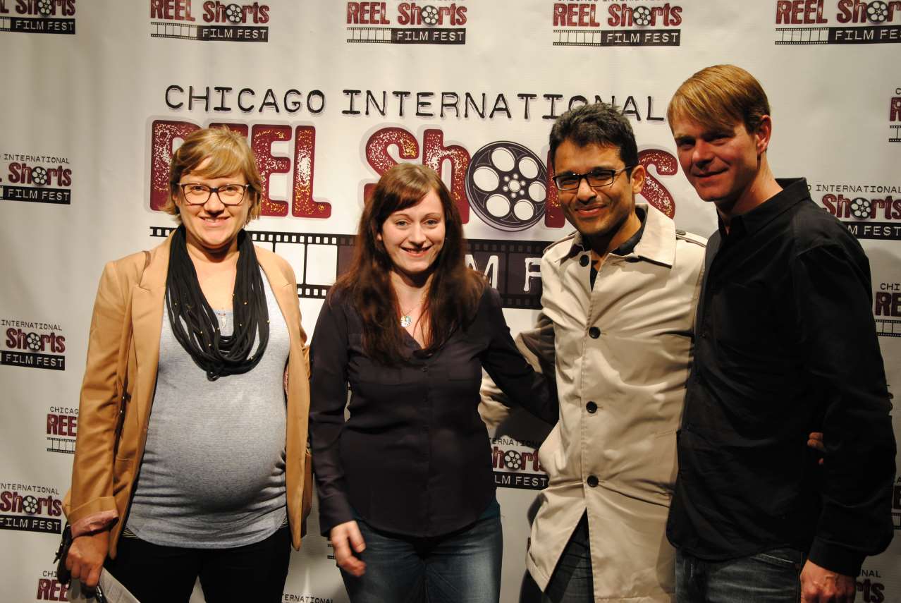 Four people pose at a Chicago film festival. A woman in a jacket, a woman in a shirt, a man in a trench coat, and a man in a sweater.