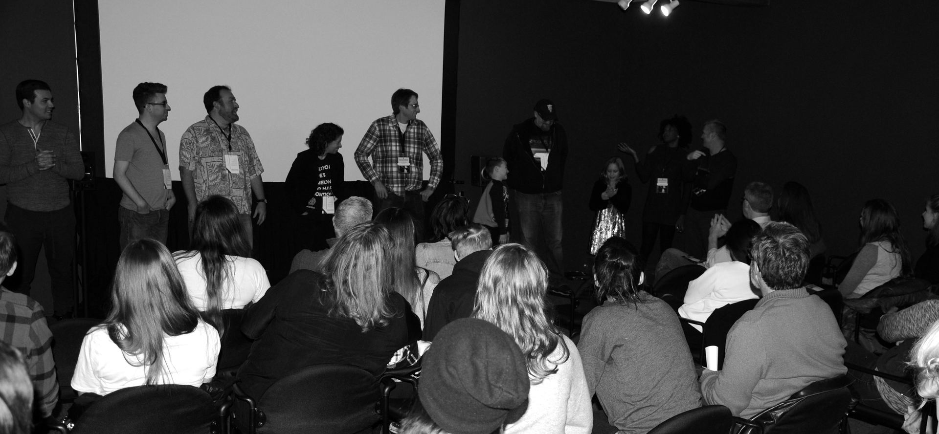A panel of people on a stage facing an audience in a dimly lit room.