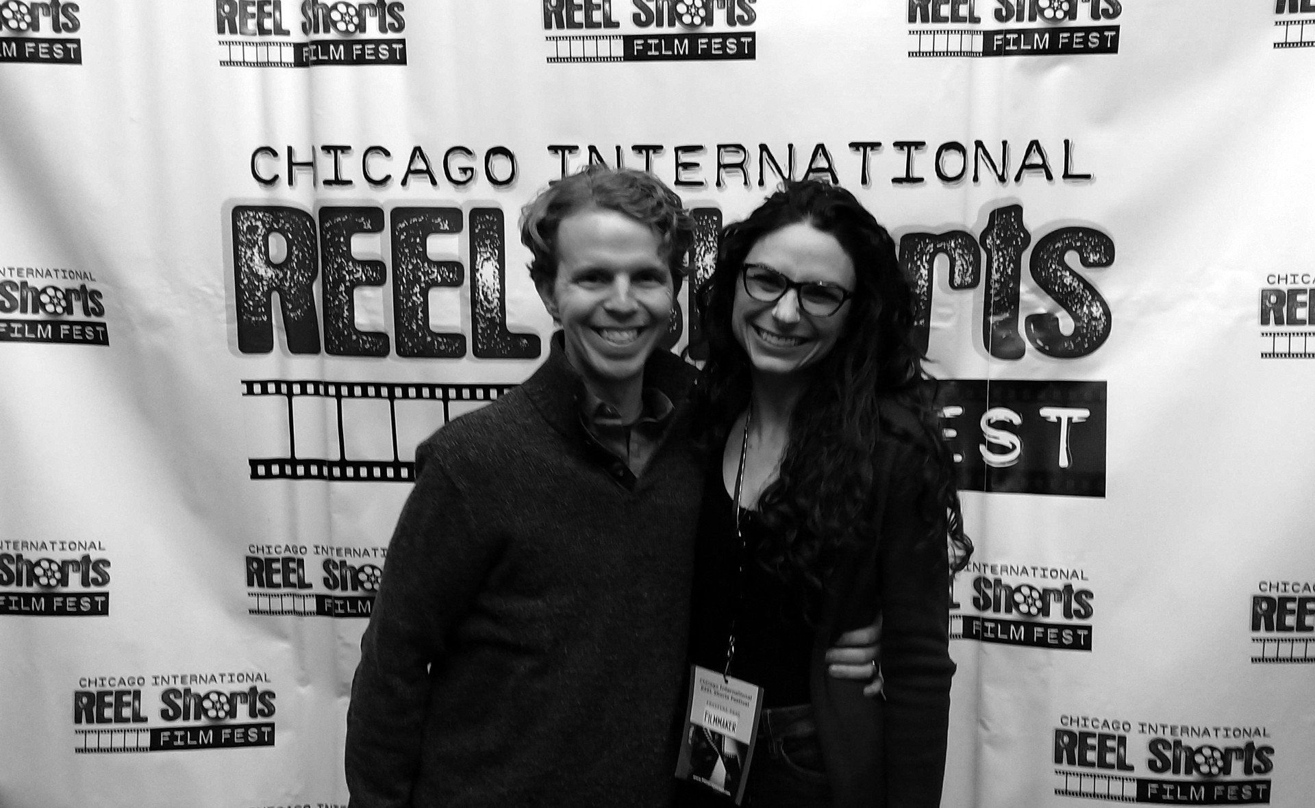 A smiling man and woman pose in front of a 