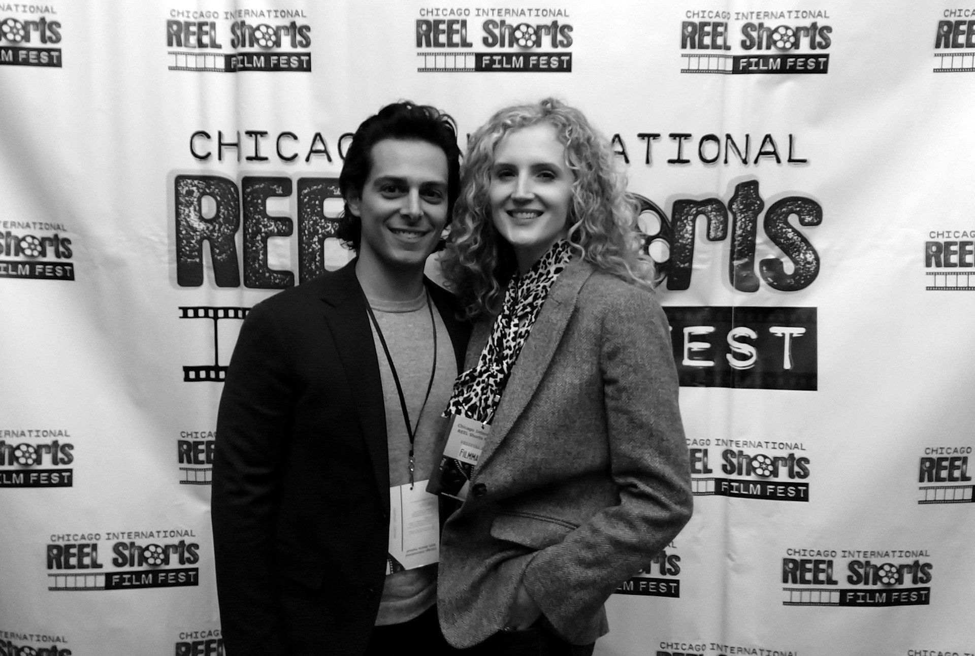 Two people smiling, posing in front of a 