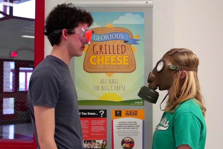 Two people, one wearing goggles, the other a gas mask, face each other near a