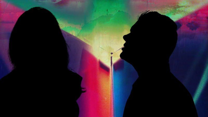 Silhouettes of a person and a man against a colorful graffiti wall.