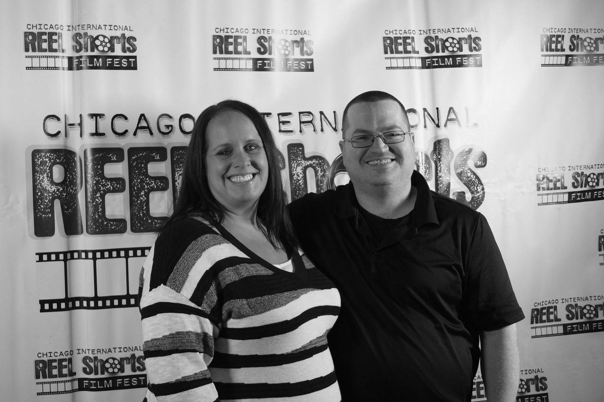 Two people smiling in front of a 