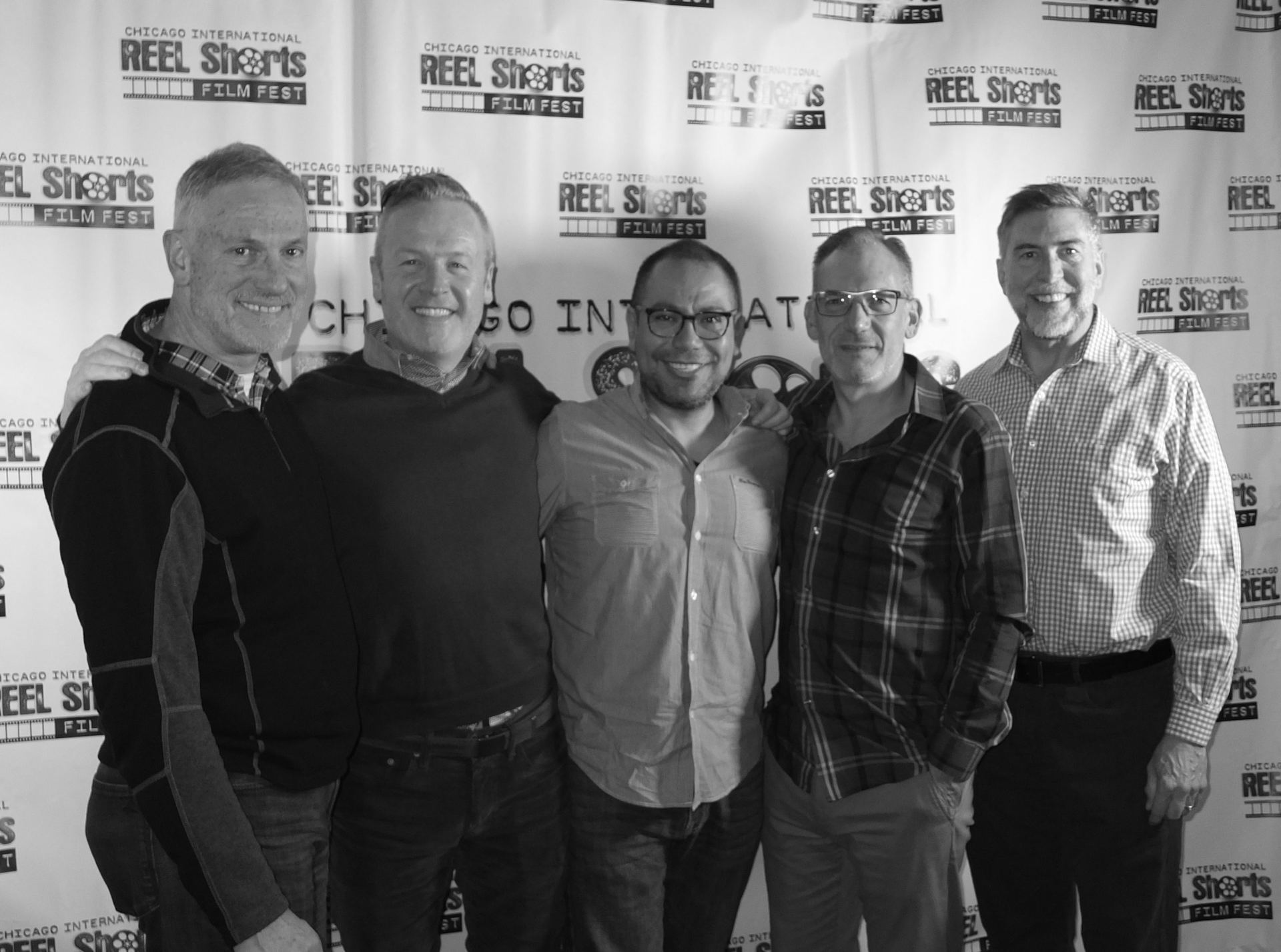 Five men pose together at an event with a 