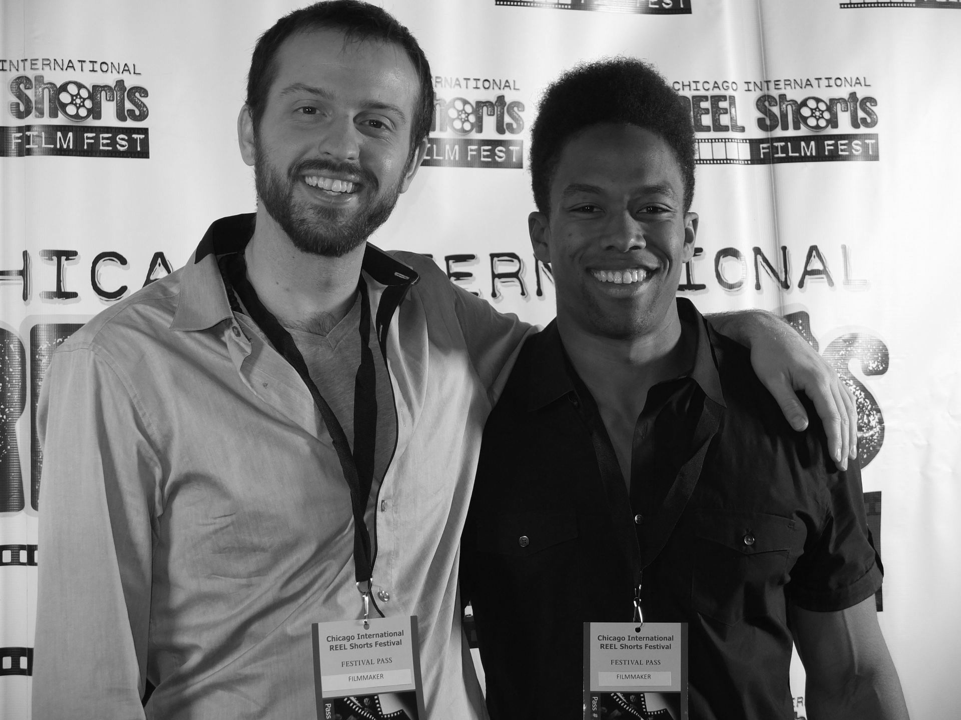 Two men at a film festival, smiling. One has his arm around the other's shoulder. Black and white.
