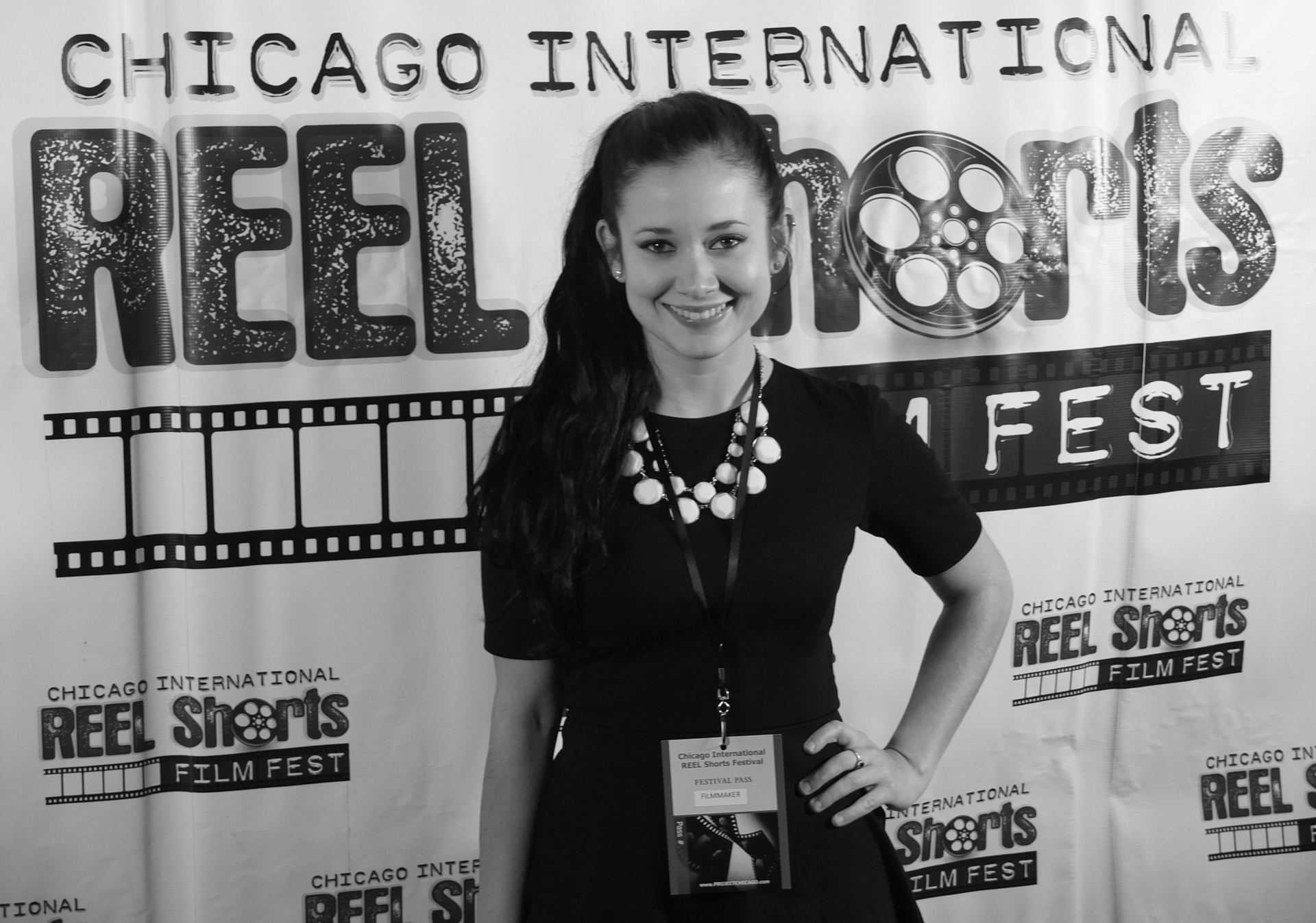 Woman at the Chicago International Reel Shorts Film Fest, smiling, wearing a black dress and necklace.