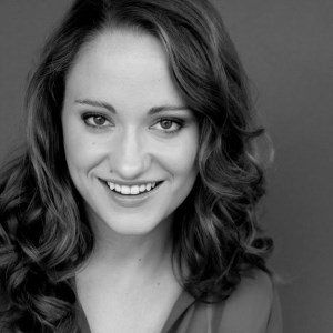 Woman with wavy hair smiles at the camera; black and white headshot.