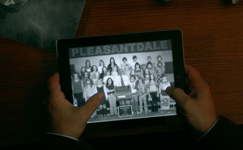 Hands holding a tablet displaying a black and white Pleasantdale school photo.