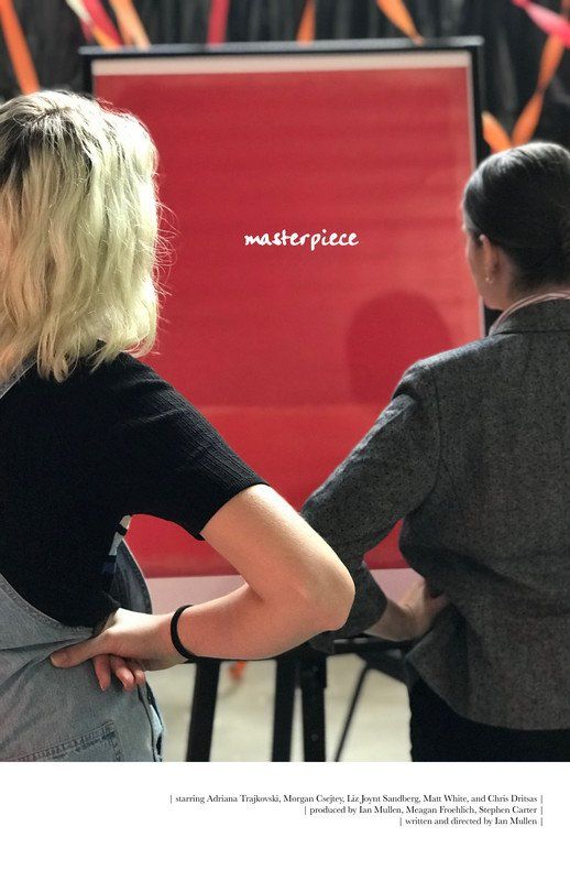 Two people looking at a red easel with the word
