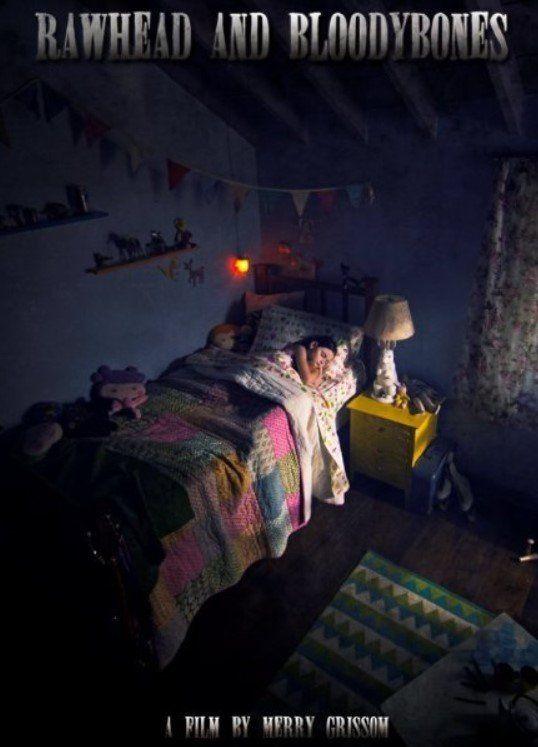 A child sleeps in a dimly lit bedroom. The room is cluttered, with toys and a colorful quilt on the bed.