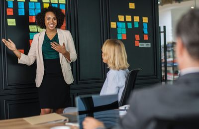 The Firm IR Group can draft comprehensive IR plans, calendars and more. Image is of a lady leading a small meeting.
