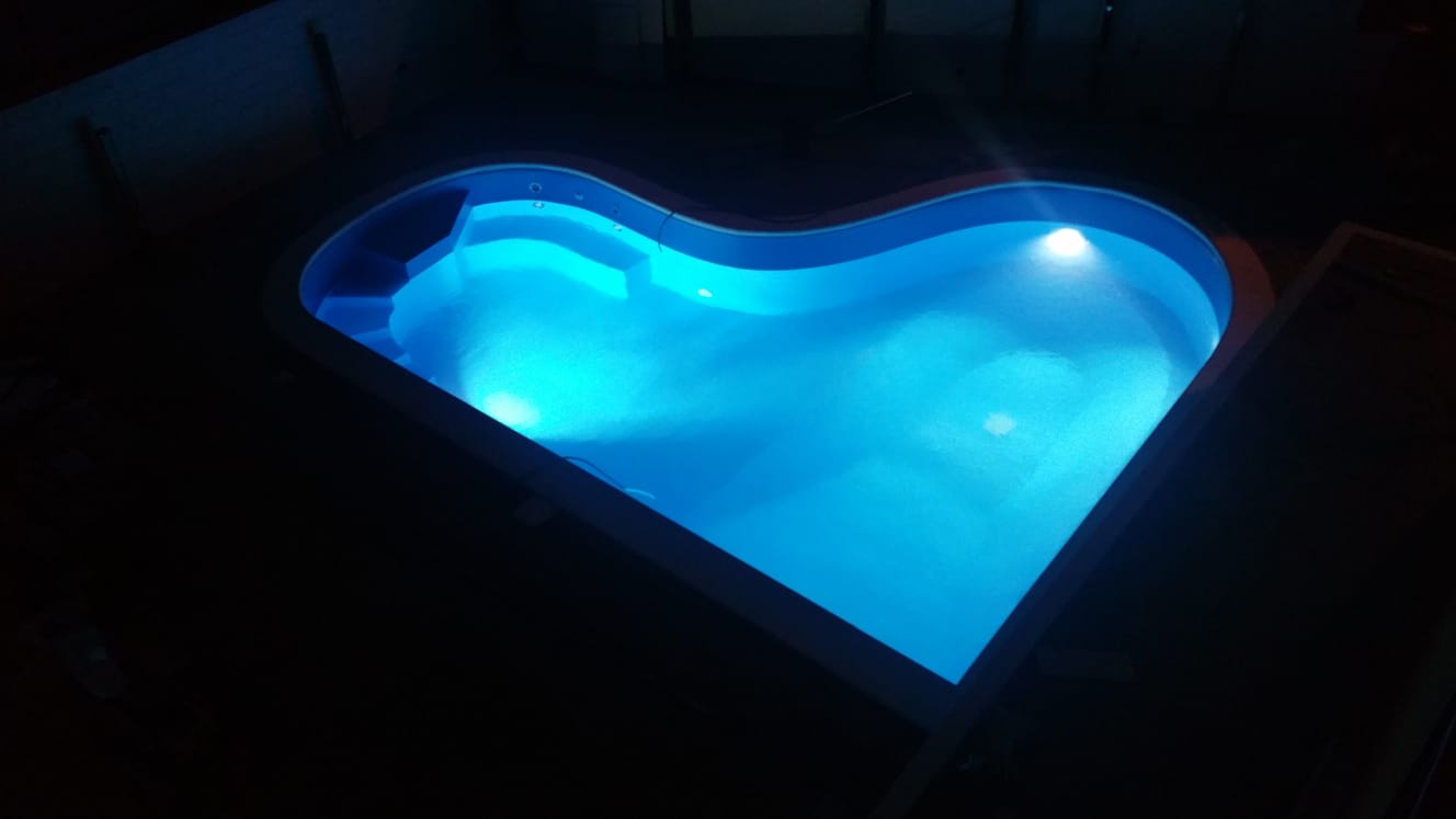 Piscina a forma di cuore illuminata di notte con luce blu.
