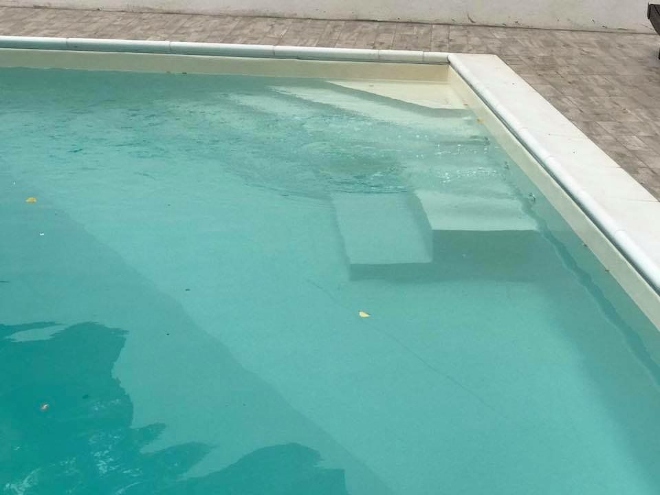 Piscina color turchese con gradini e bordi bianchi.