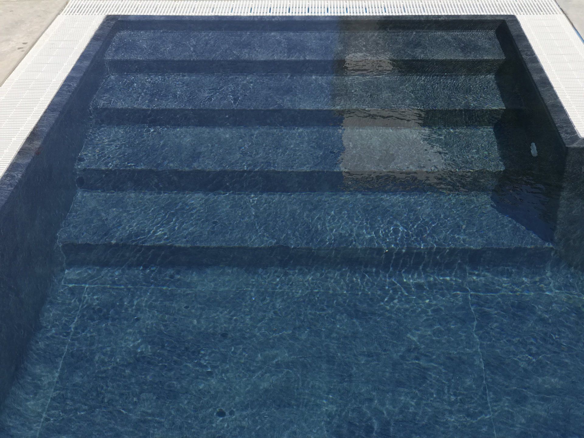 Gradini della piscina in acqua blu scuro, con bordi di colore chiaro.