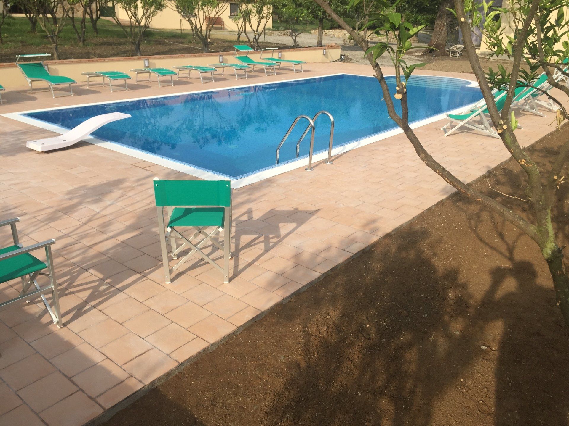 Piscina circondata da sedie a sdraio, in un ambiente all'aperto.