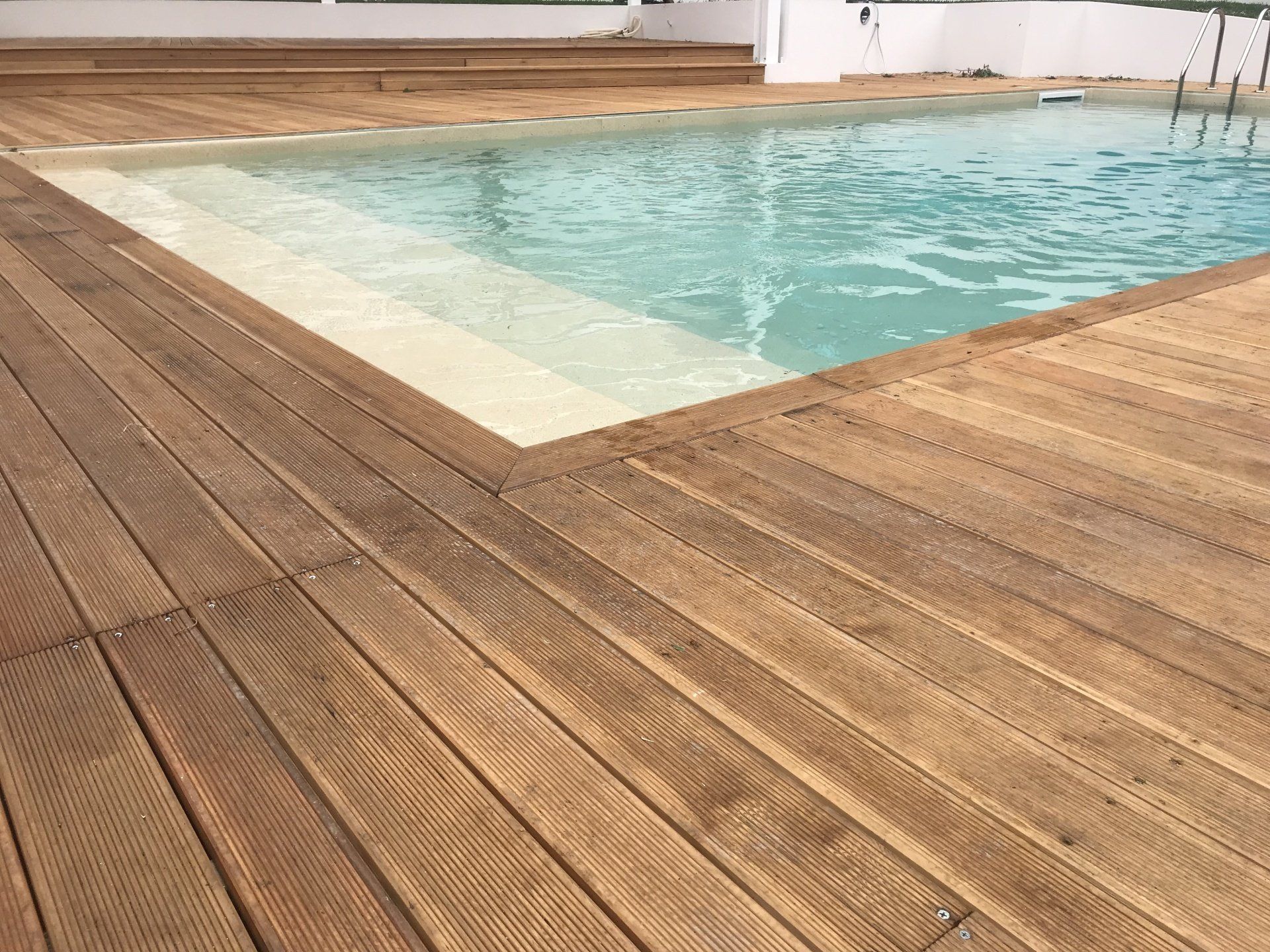 Un ponte di legno circonda una piscina con acqua azzurra.