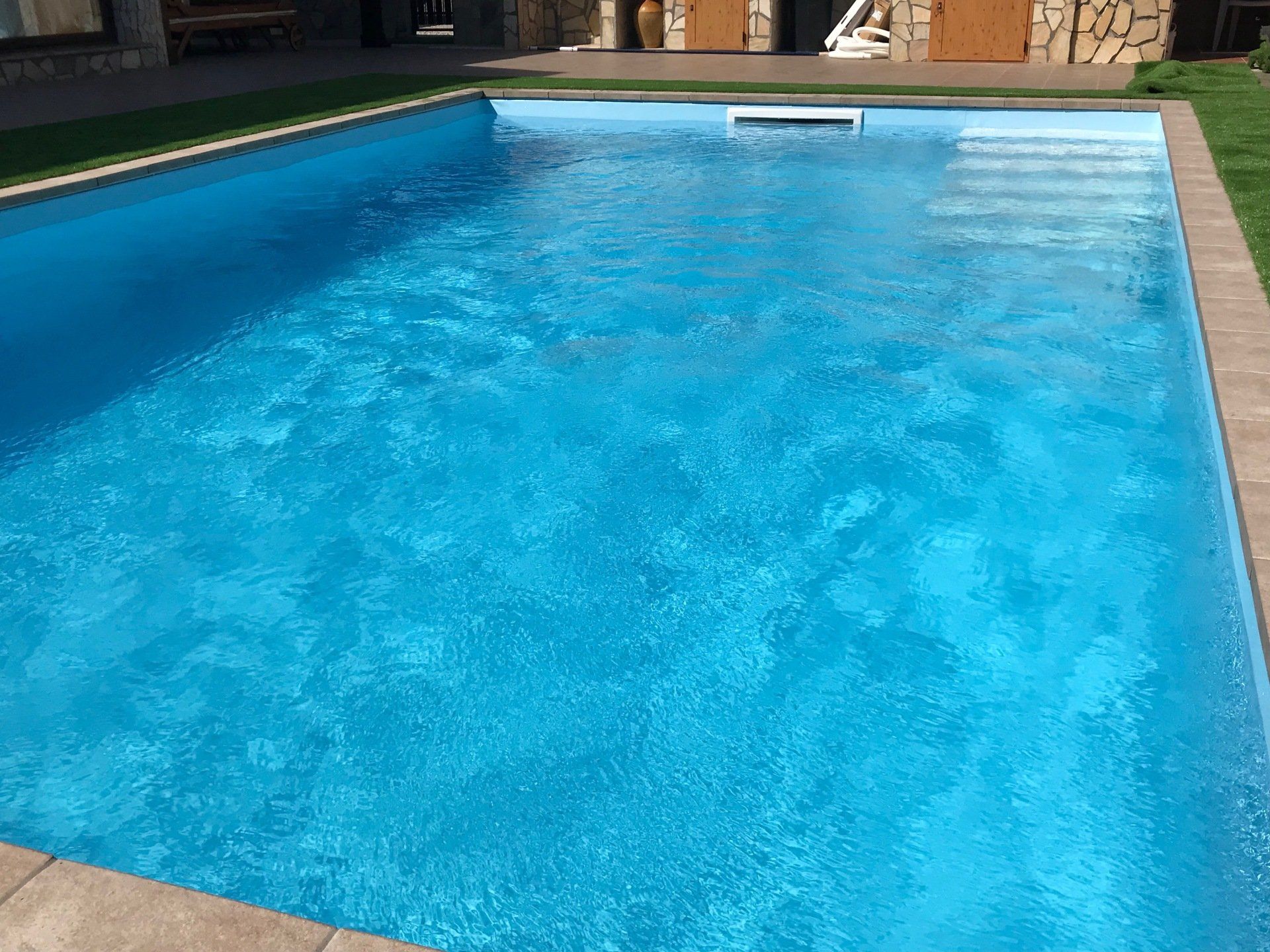 Piscina blu con acqua gorgogliante e bordo in pietra.