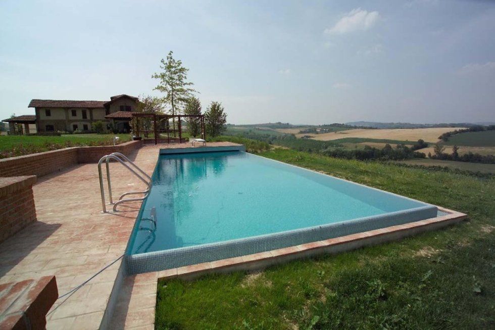 Piscina con vista sulla campagna e una casa in lontananza.