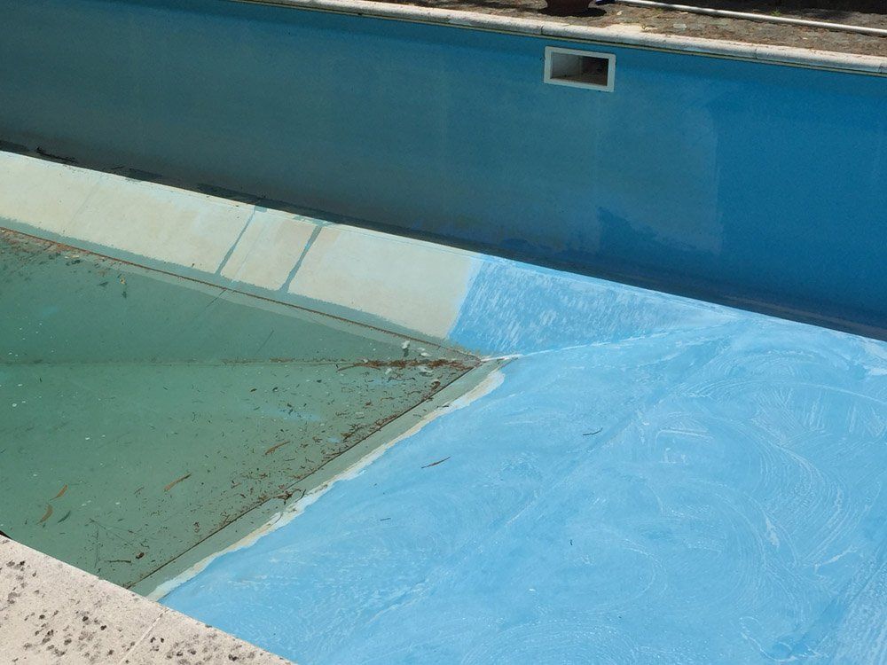 Piscina vuota con superfici turchesi e verdi, con filtro e sporgenze angolate.