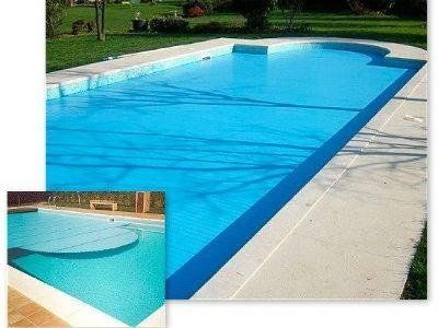 Una piscina blu con bordi in cemento e un'immagine più piccola inserita della piscina con una copertura circolare.