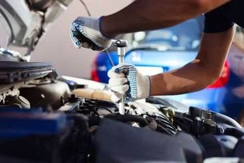 due mani che con un cacciavite a t operano su un motore di una vettura due mani che con un cacciavite a t operano su un motore di una vettura