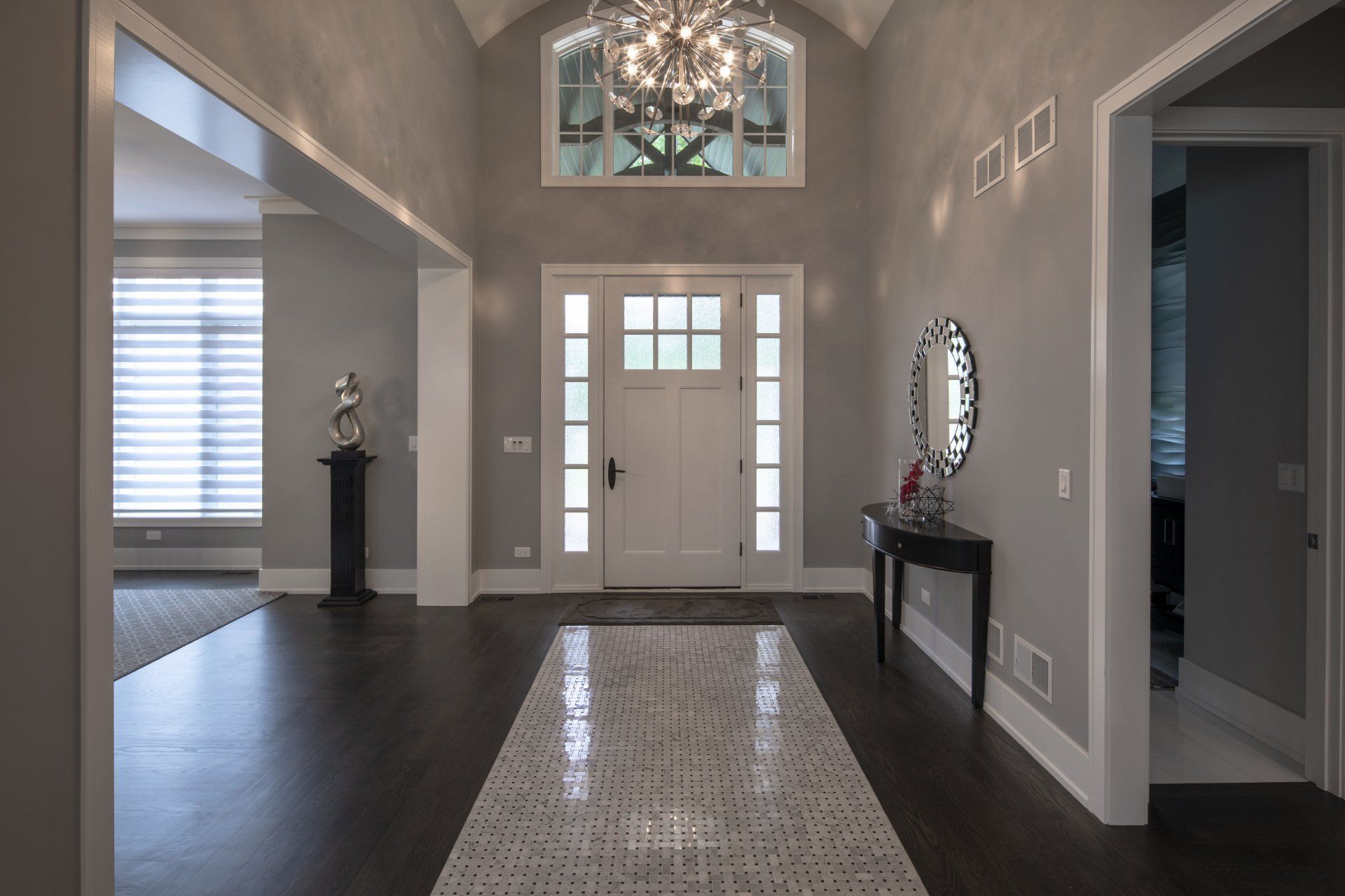 A large hallway in a house with a chandelier hanging from the ceiling.