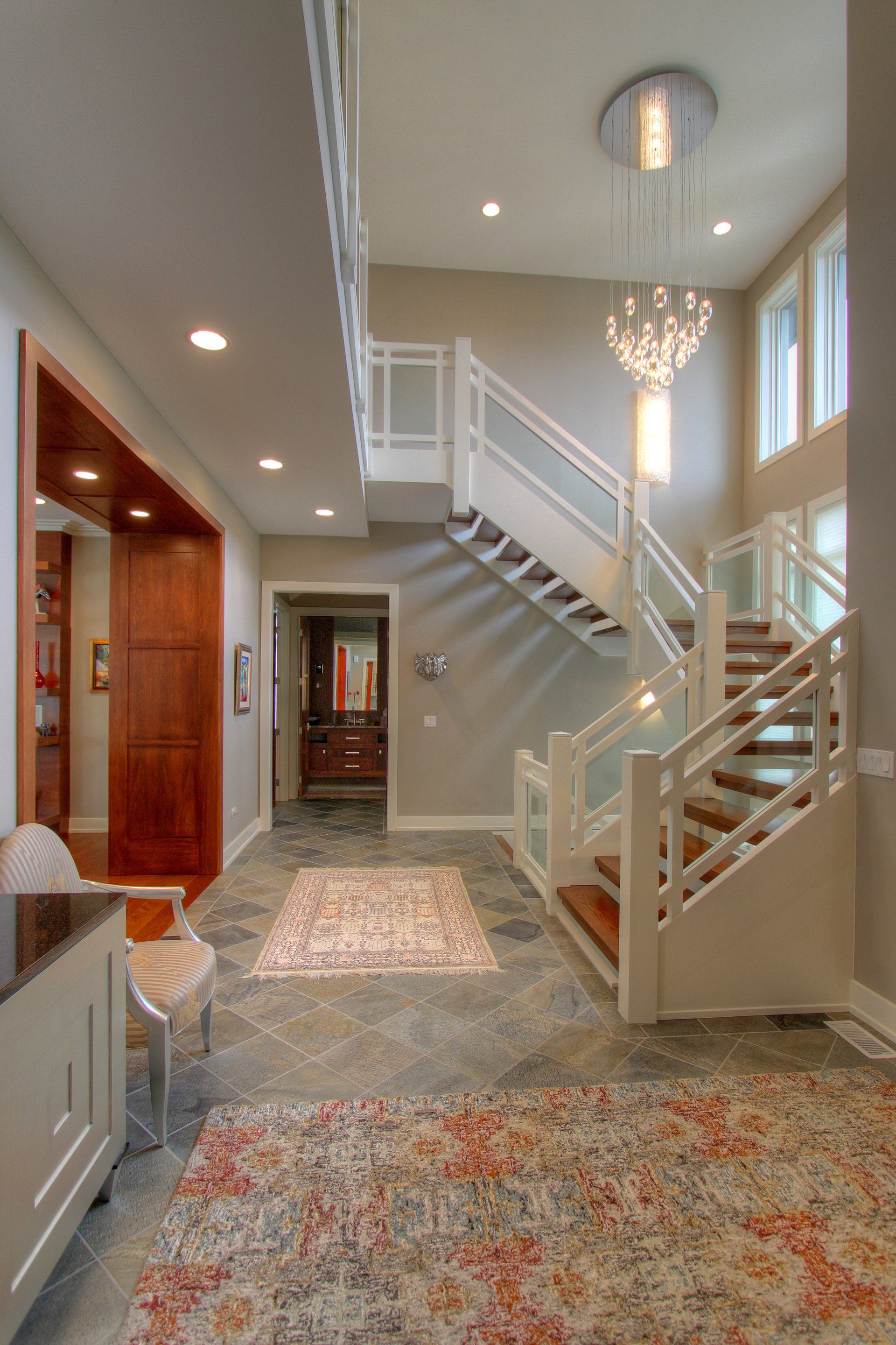 A large hallway with a staircase and a chandelier.