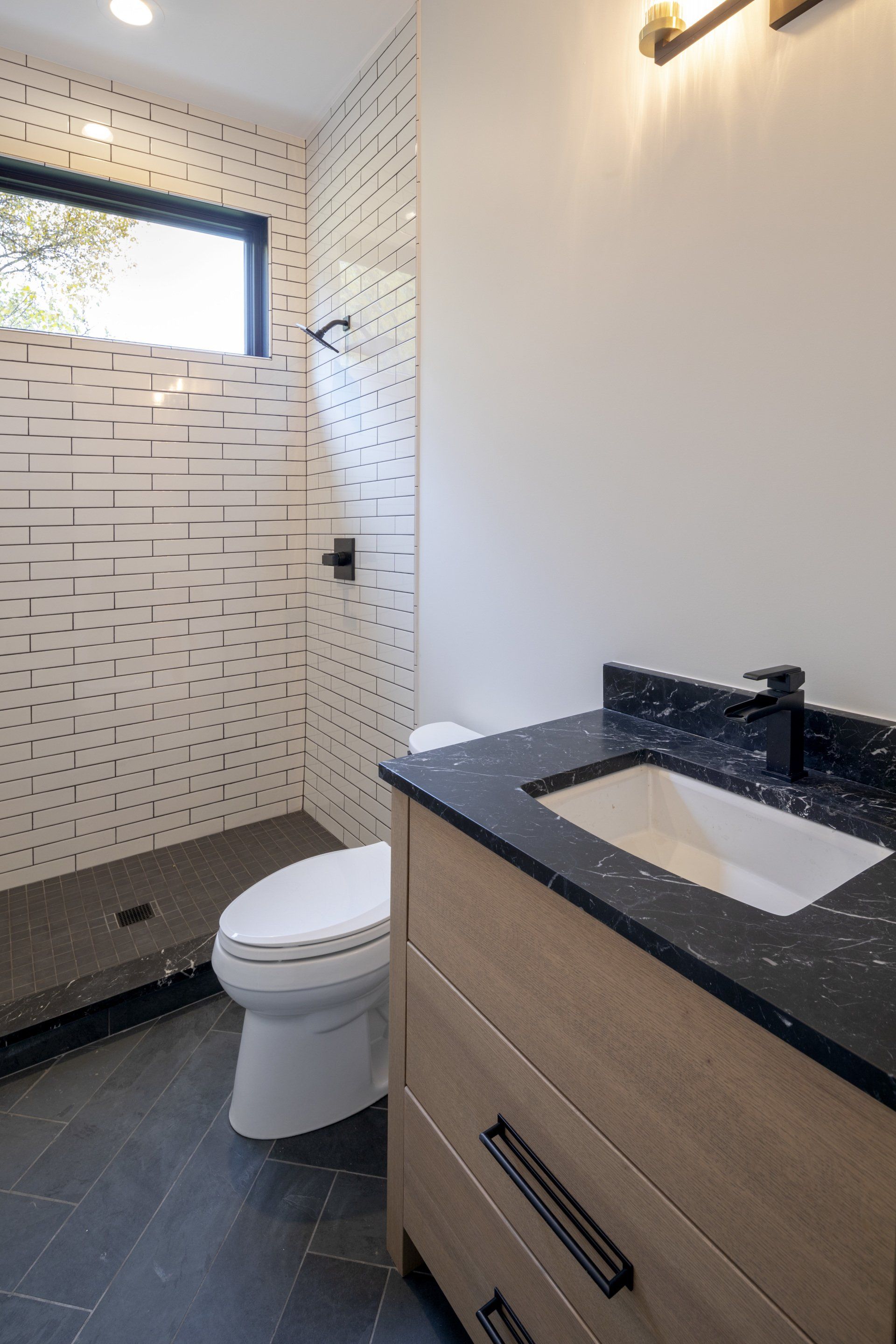 A bathroom with a toilet , sink and shower.
