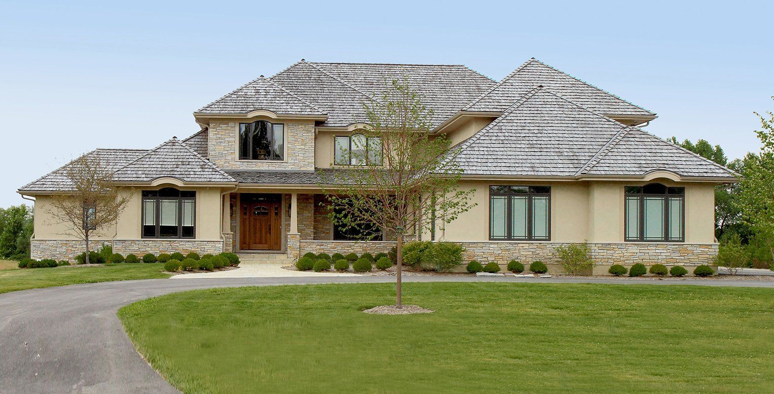 A large house with a thatched roof sits in the middle of a lush green field