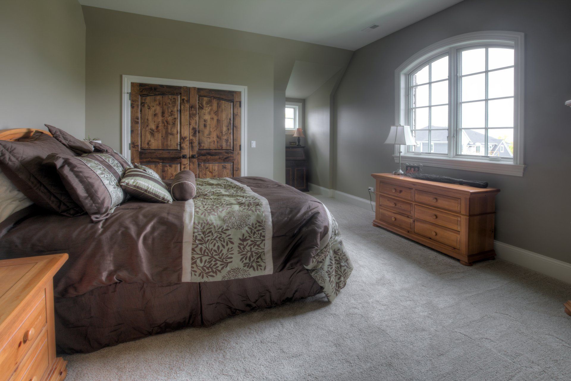 A bedroom with a bed , dresser , nightstand and window.