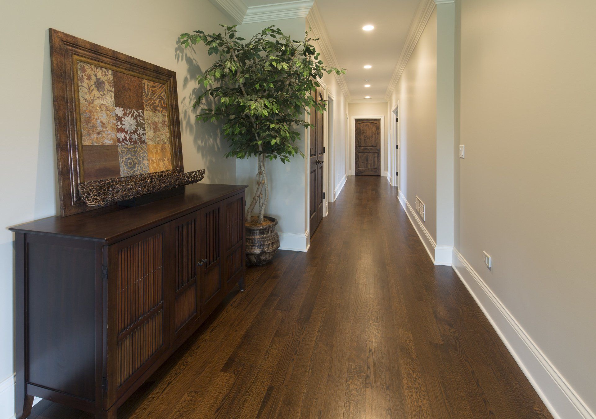 A long hallway with hardwood floors and a dresser