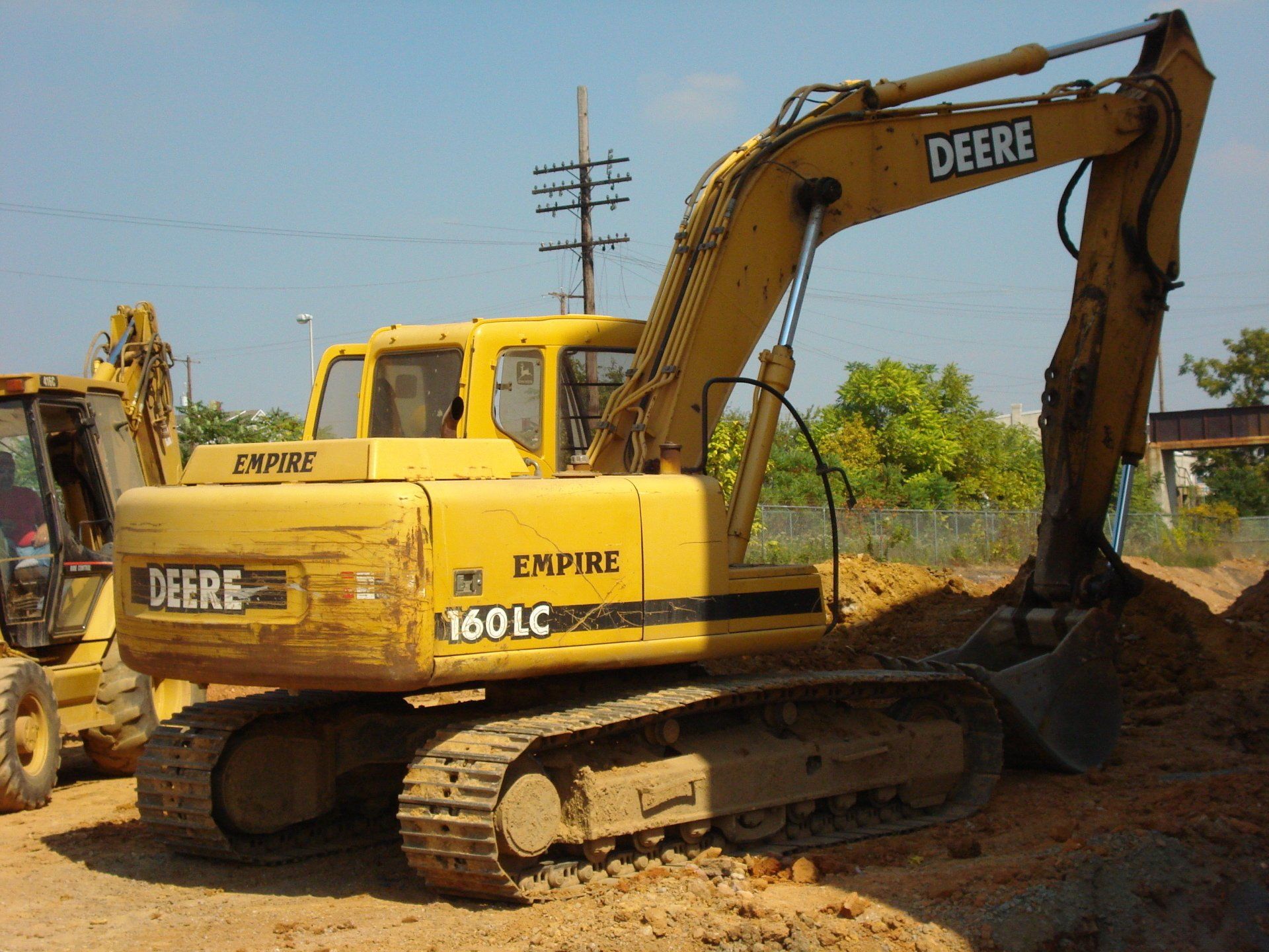 A yellow deere excavator is parked in the dirt