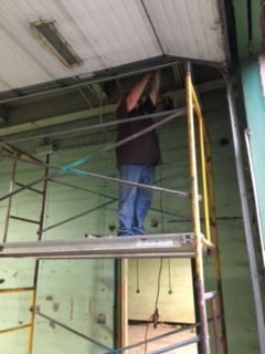 A man is standing on a scaffolding working on a garage door