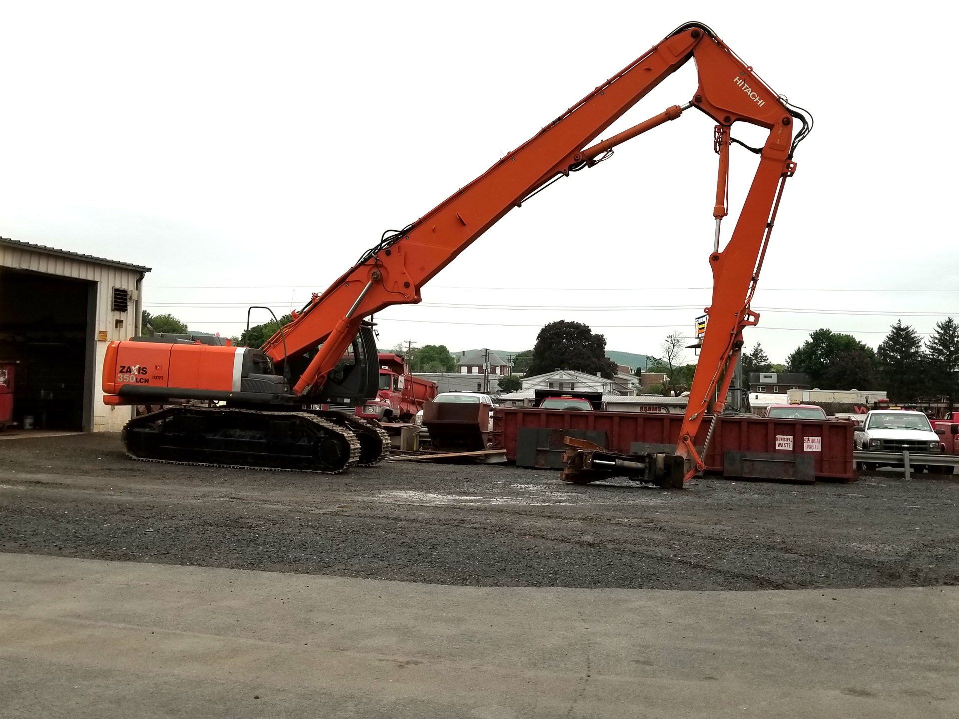 A large orange excavator is parked in a gravel lot