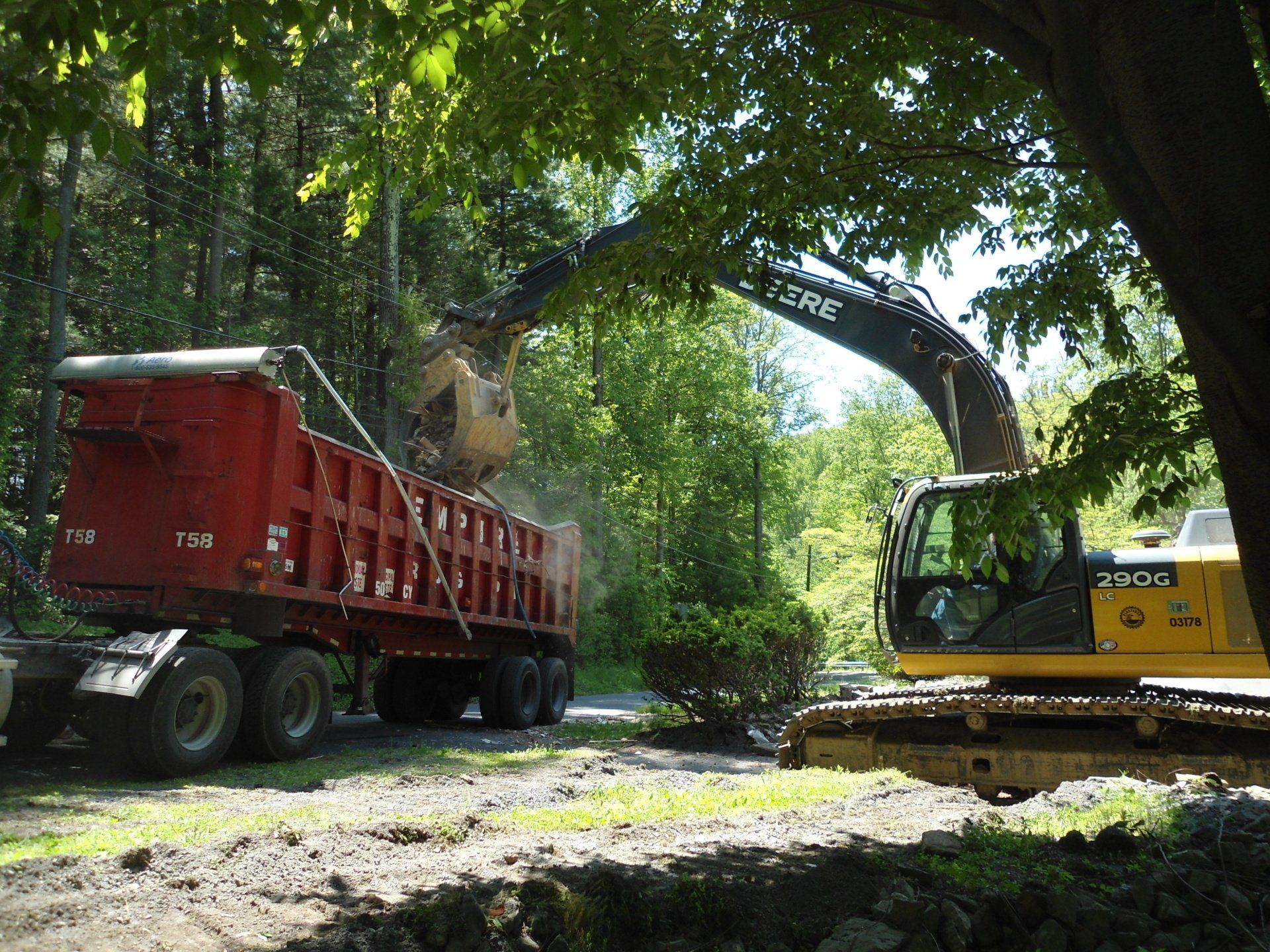 A dump truck is being loaded with dirt by a deere excavator