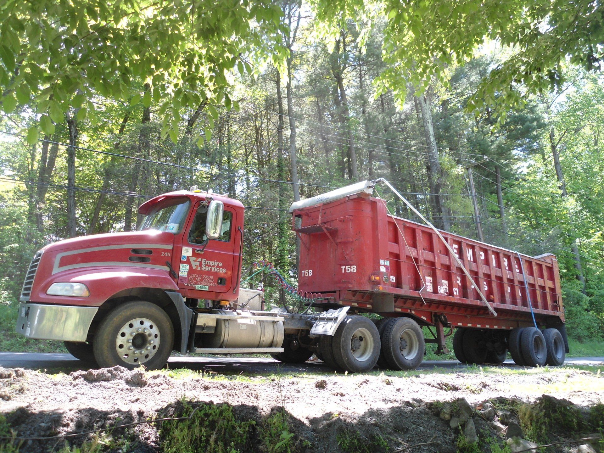 A red dump truck is parked on the side of the road.